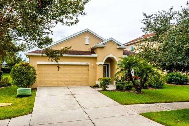 view of front of house with an attached garage, a front lawn, concrete driveway, and stucco siding