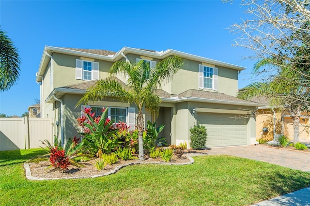 view of front facade with decorative driveway, stucco siding, a front yard, fence, and a garage