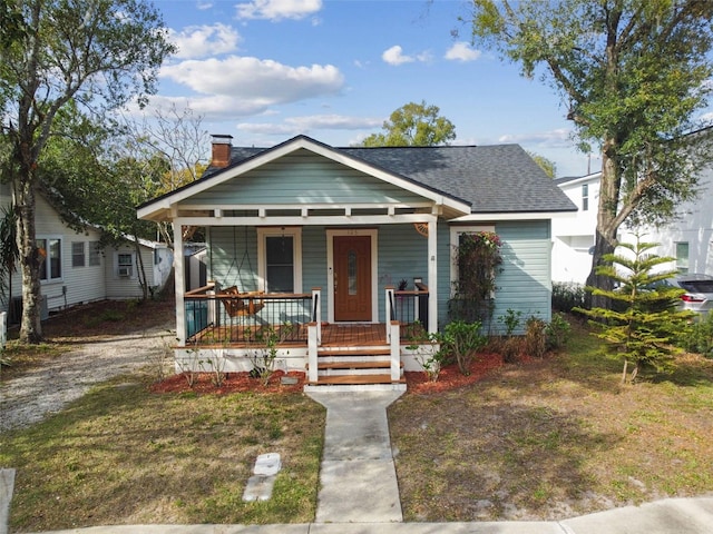 bungalow-style house featuring a shingled roof, a front lawn, and a porch