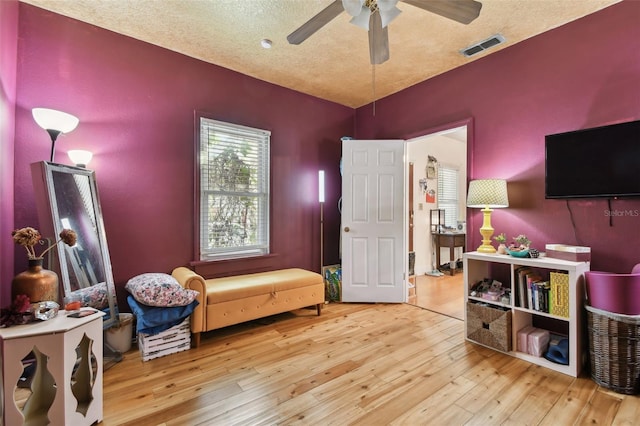 recreation room with light wood-style floors, visible vents, ceiling fan, and a textured ceiling