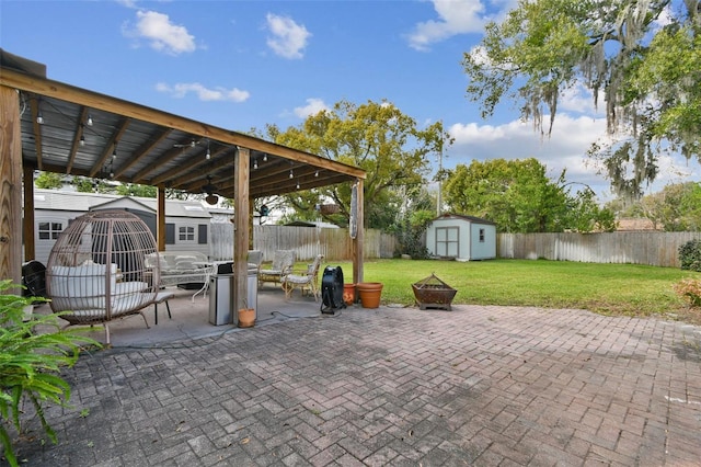 view of patio / terrace with a fenced backyard, a fire pit, an outdoor structure, a storage unit, and outdoor dining space