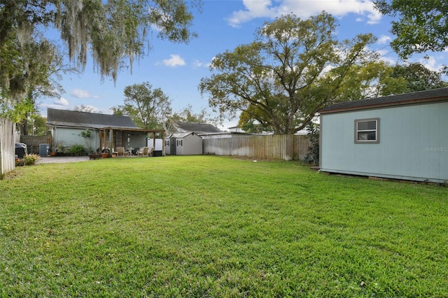 view of yard with an outbuilding, a storage unit, and a fenced backyard