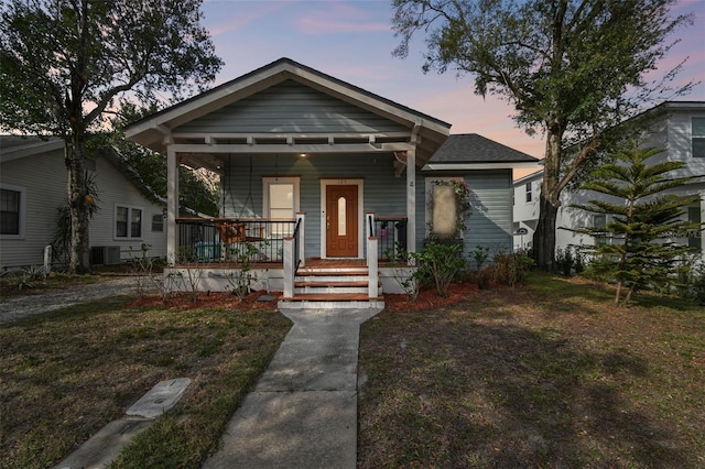 bungalow-style home with central air condition unit, a front lawn, and a porch