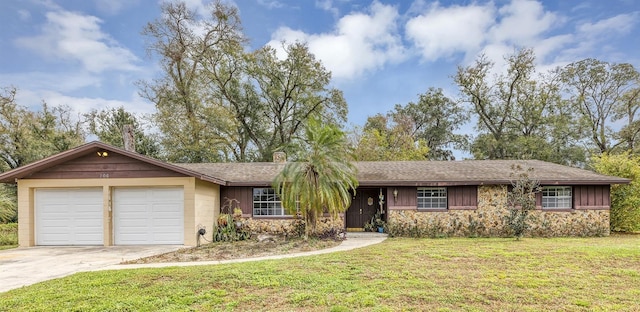 ranch-style house featuring an attached garage, stone siding, concrete driveway, board and batten siding, and a front yard