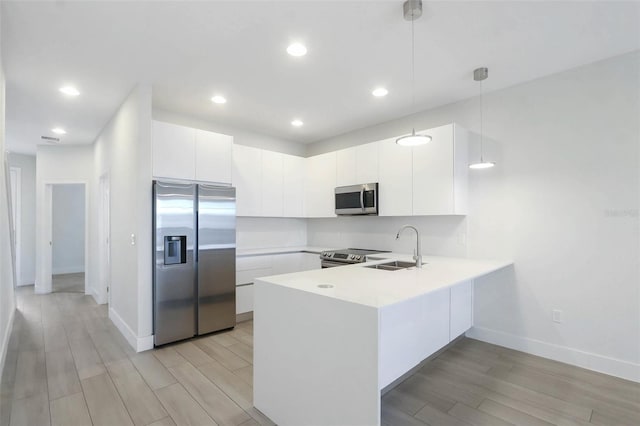 17442 Hidden Forest Dr, Clermont, FL 34714 - kitchen with stainless steel appliances, a peninsula, a sink, light wood-style flooring, and white cabinets