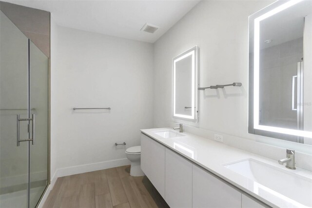 17442 Hidden Forest Dr, Clermont, FL 34714 - bathroom with toilet, wood finished floors, a stall shower, double vanity, and baseboards