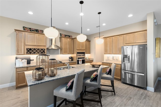 kitchen with a sink, stainless steel fridge with ice dispenser, light brown cabinetry, wood tiled floor, and wall chimney exhaust hood