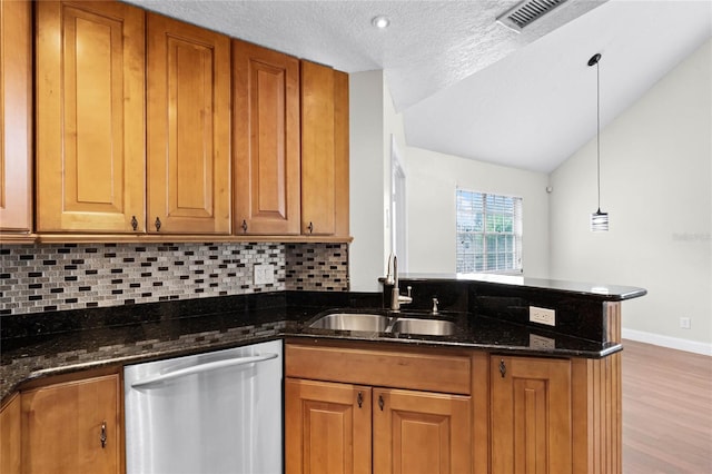 kitchen with dark stone counters, dishwasher, brown cabinets, decorative light fixtures, and a sink