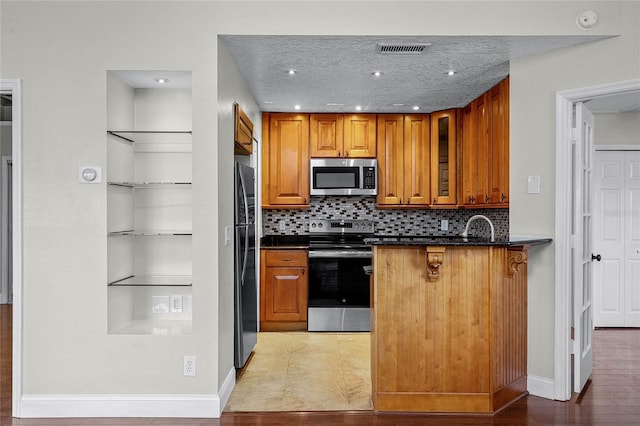 kitchen with dark countertops, brown cabinetry, and stainless steel appliances