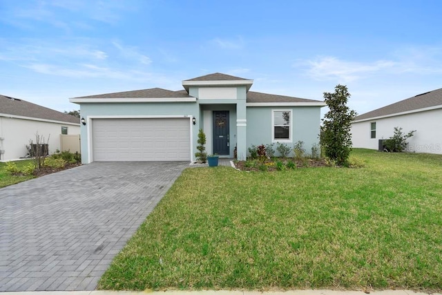 view of front of house featuring decorative driveway, a front yard, an attached garage, and stucco siding