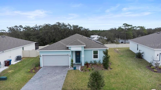 ranch-style home featuring central AC unit, concrete driveway, an attached garage, fence, and a front lawn