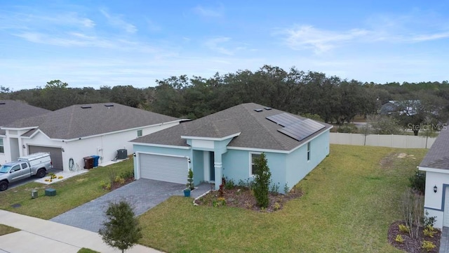 view of front of house with a garage, solar panels, fence, driveway, and a front yard