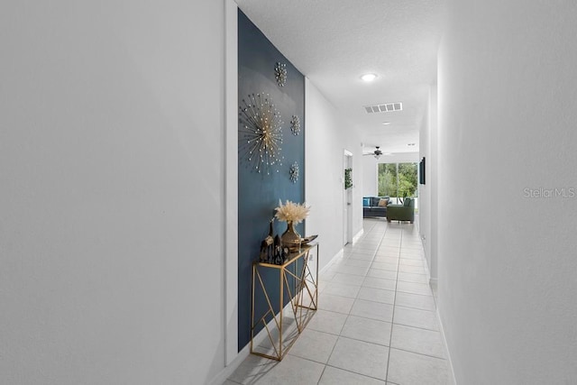 hall featuring light tile patterned floors, visible vents, and baseboards