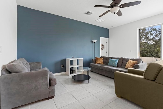 living area with light tile patterned floors, ceiling fan, visible vents, and baseboards