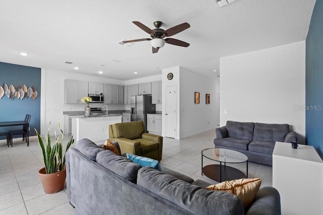 living room with light tile patterned floors, baseboards, visible vents, a ceiling fan, and recessed lighting