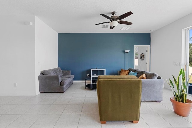 living room featuring light tile patterned floors, ceiling fan, visible vents, and baseboards