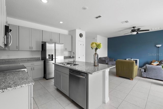 kitchen featuring visible vents, appliances with stainless steel finishes, open floor plan, light tile patterned flooring, and a sink