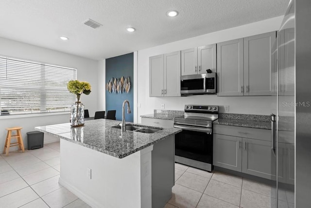 kitchen featuring stainless steel appliances, gray cabinets, a sink, and visible vents