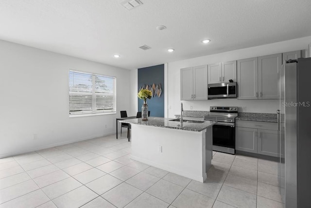 kitchen featuring light tile patterned floors, stone countertops, a sink, appliances with stainless steel finishes, and gray cabinets