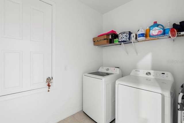 washroom with laundry area, washer and clothes dryer, baseboards, and light tile patterned floors