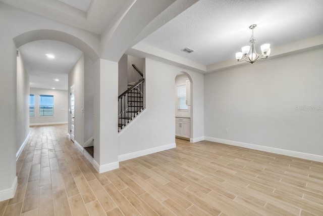 interior space featuring stairway, baseboards, arched walkways, and light wood finished floors