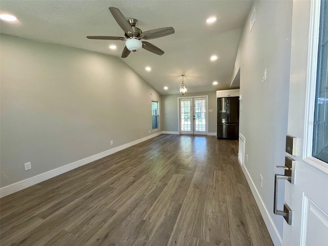 unfurnished living room featuring lofted ceiling, recessed lighting, dark wood-type flooring, baseboards, and french doors