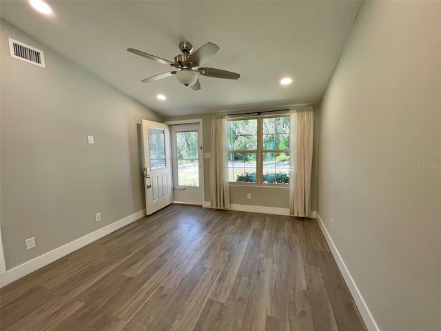 interior space with visible vents, dark wood-type flooring, a ceiling fan, vaulted ceiling, and baseboards