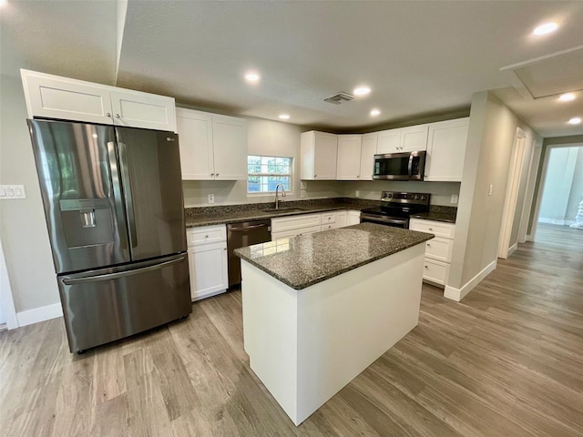 kitchen with light wood-style flooring, white cabinetry, stainless steel appliances, and a sink