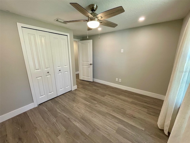 unfurnished bedroom with baseboards, a ceiling fan, wood finished floors, a textured ceiling, and a closet