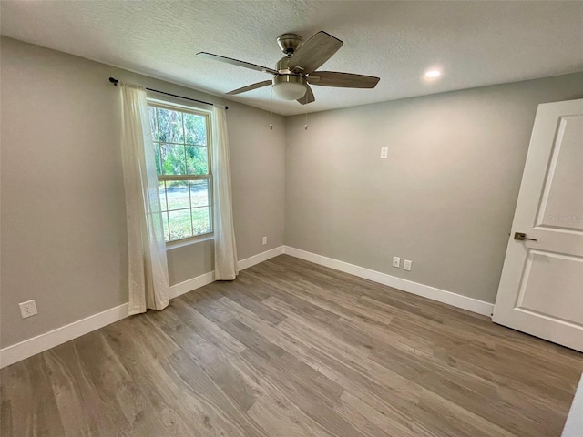 empty room featuring a ceiling fan, a textured ceiling, baseboards, and wood finished floors