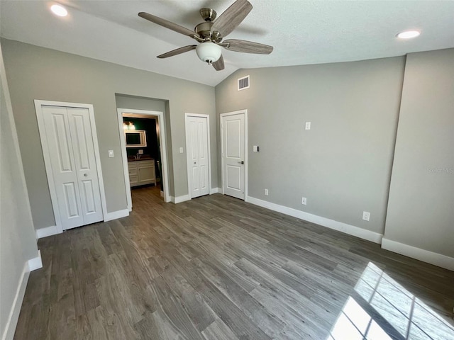 unfurnished bedroom with visible vents, dark wood-type flooring, and multiple closets