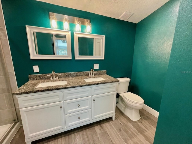 bathroom with toilet, double vanity, a sink, and wood finished floors