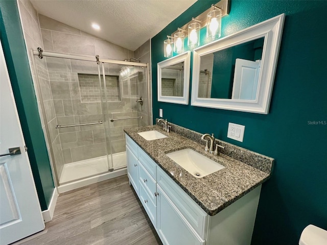 bathroom featuring a shower stall, vaulted ceiling, a sink, and wood finished floors