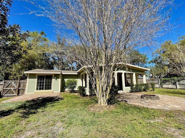 view of front of house featuring a front yard, a patio area, fence, and a fire pit