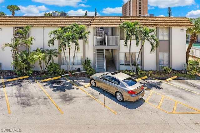 view of property featuring stairs and uncovered parking