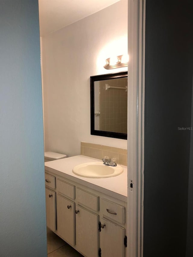 bathroom featuring toilet, tile patterned flooring, backsplash, and vanity