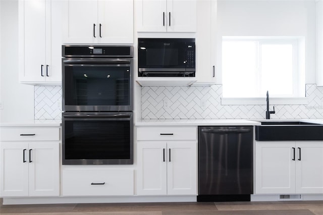 kitchen featuring light countertops, black appliances, and white cabinetry