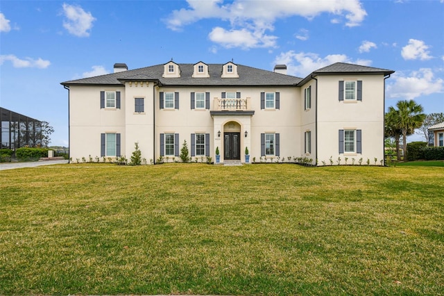 view of front of property featuring a balcony, stucco siding, a chimney, and a front yard