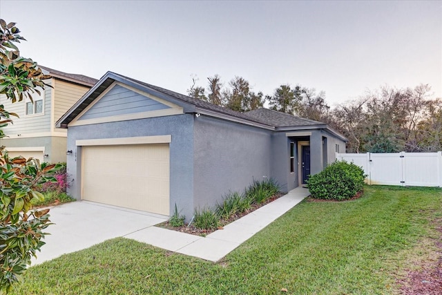 view of front of house featuring a garage, fence, a gate, stucco siding, and a front yard