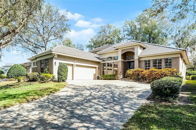 prairie-style house with a garage, a tiled roof, decorative driveway, and stucco siding