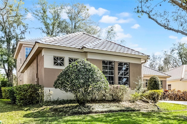 view of property exterior with a yard, a tiled roof, and stucco siding