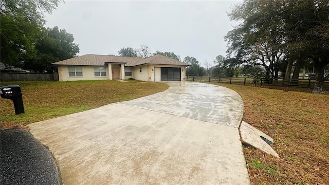 view of front of home featuring a front yard, concrete driveway, fence, and an attached garage