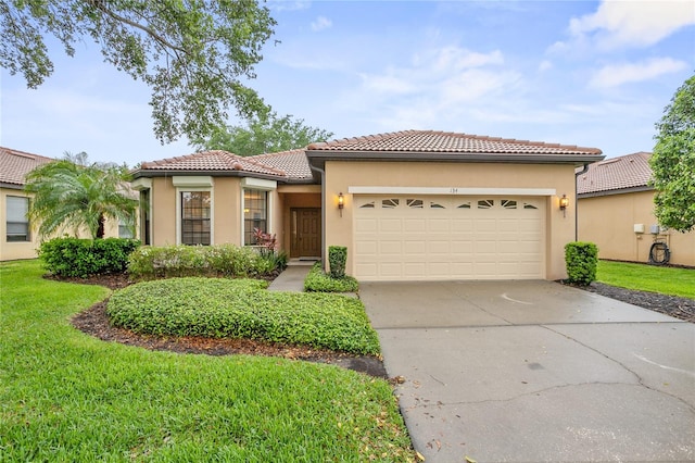 mediterranean / spanish-style house with driveway, a tiled roof, an attached garage, a front lawn, and stucco siding