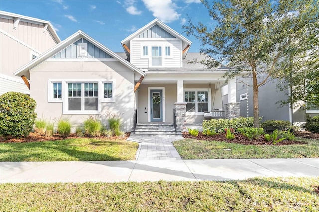 craftsman-style house with covered porch, a front lawn, and board and batten siding