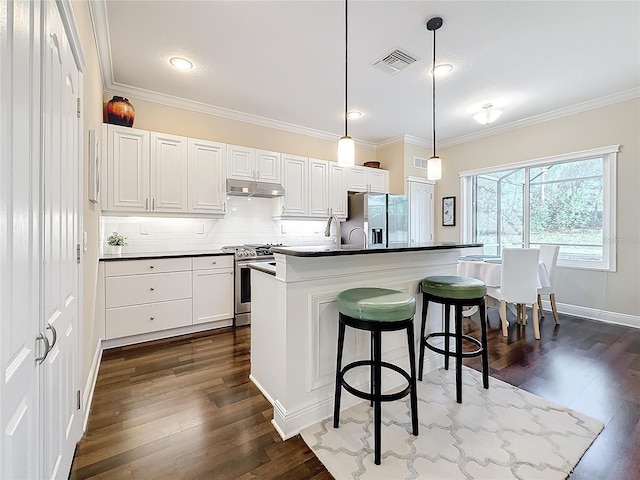 kitchen featuring white cabinetry, appliances with stainless steel finishes, a center island, dark countertops, and pendant lighting