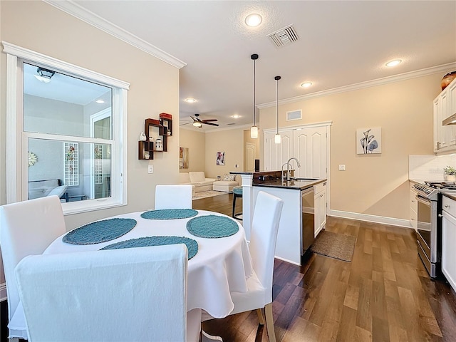 dining room with dark wood-style floors, visible vents, crown molding, and a ceiling fan