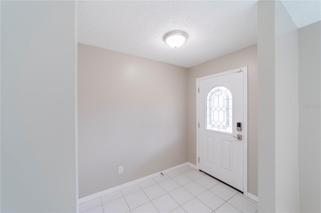 foyer entrance featuring baseboards, a textured ceiling, and light tile patterned flooring