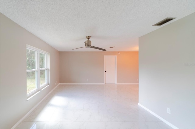 unfurnished room featuring marble finish floor, baseboards, visible vents, and a textured ceiling