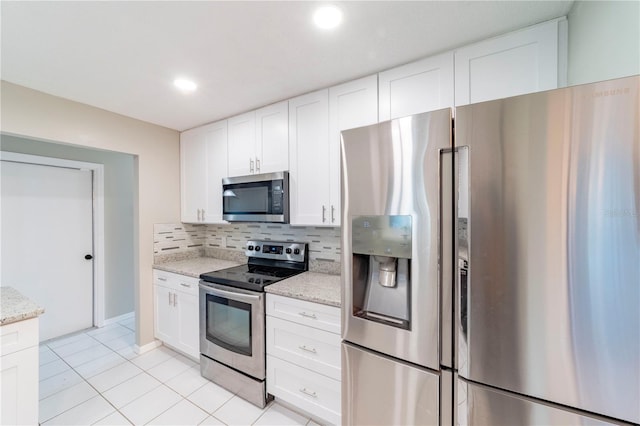 kitchen with stainless steel appliances, backsplash, white cabinetry, and light stone countertops