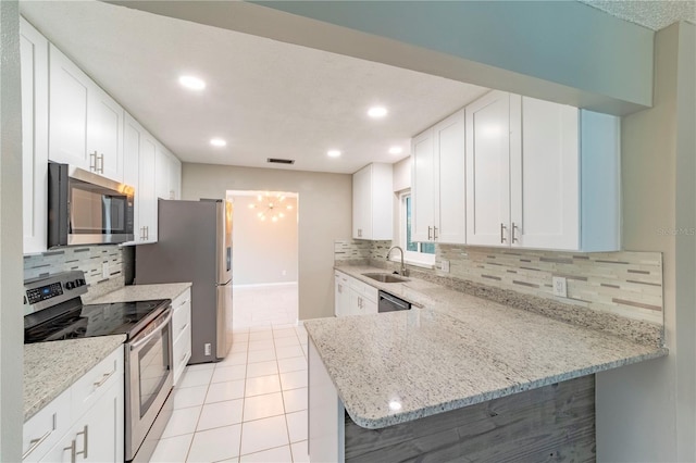 kitchen featuring light stone countertops, appliances with stainless steel finishes, white cabinets, and a sink